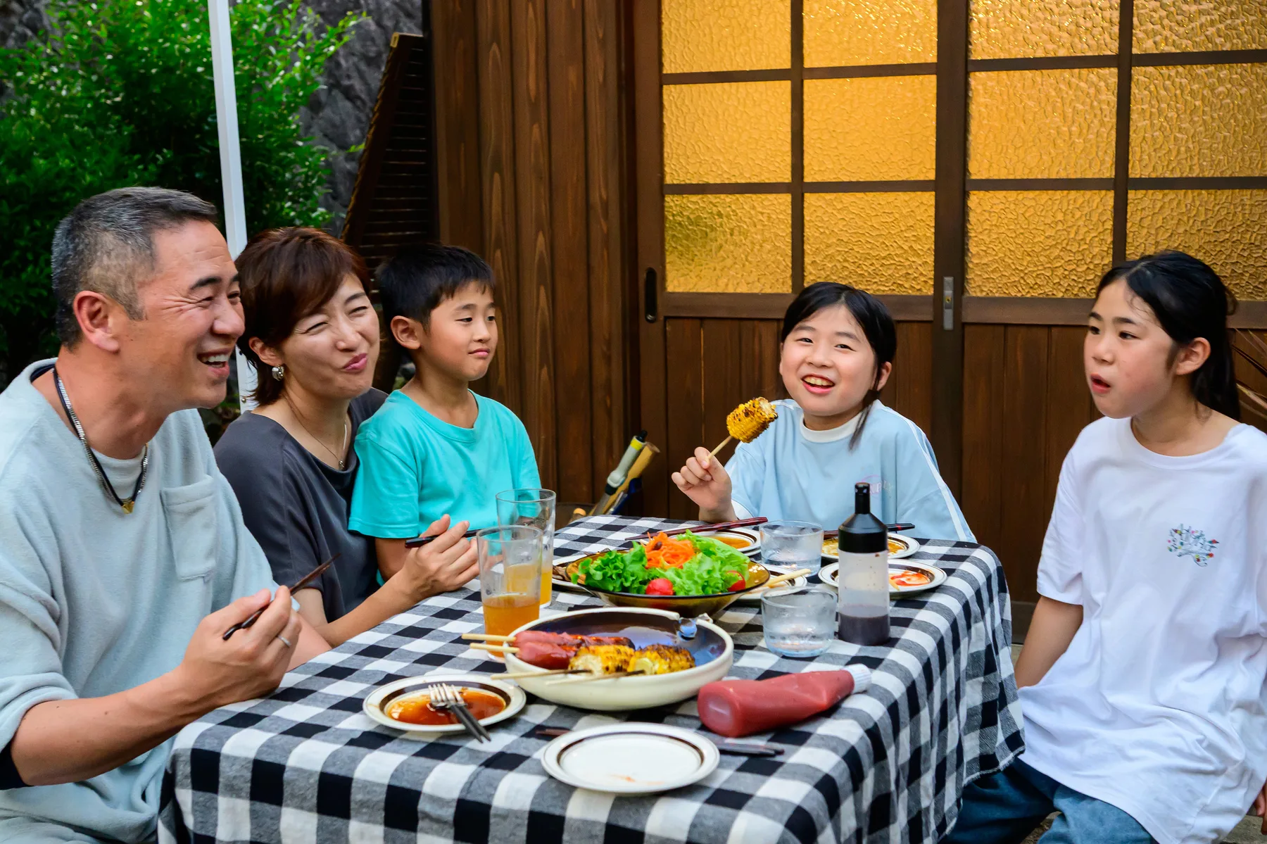 屋外の食卓を囲んで食事を楽しむ家族